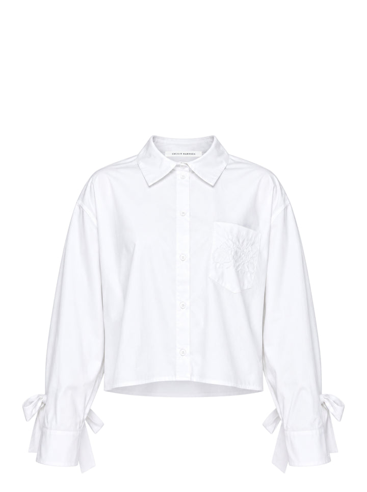 Cecilie Bahnsen Frina cropped white cotton shirt with bow-tied flared cuffs, tonal floral embroidered chest pocket, and button-through front placket, displayed flat on a white background
