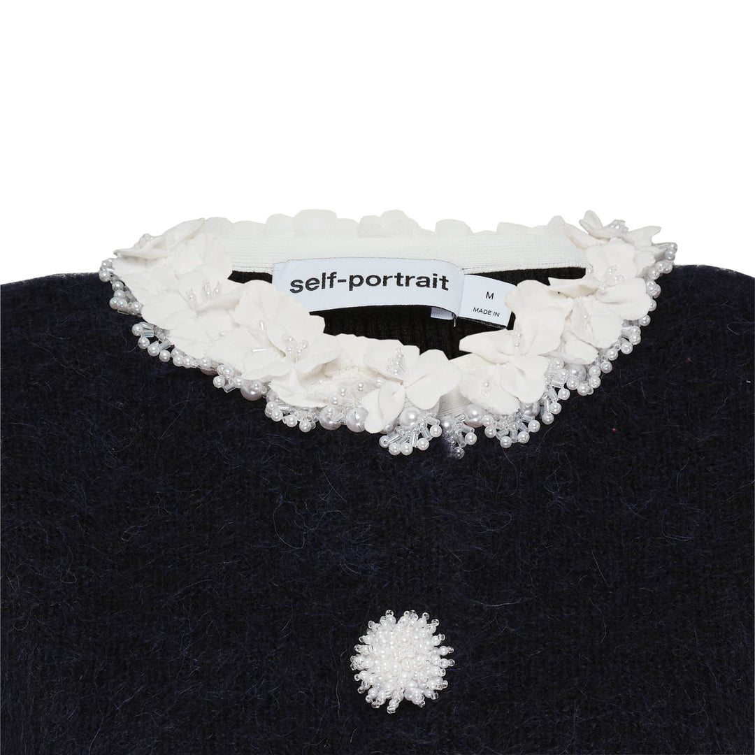 Self-Portrait black chenille ribbed knit mini dress with white floral trim at neckline, cuffs, and patch pockets, daisy button front fastening, fit-and-flare silhouette