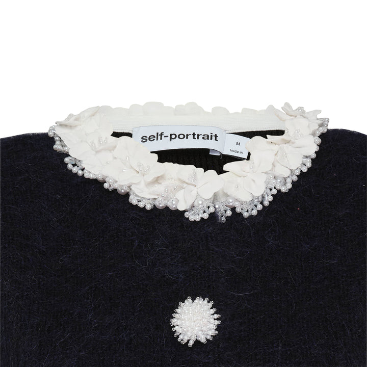 Self-Portrait black chenille ribbed knit mini dress with white floral trim at neckline, cuffs, and patch pockets, daisy button front fastening, fit-and-flare silhouette