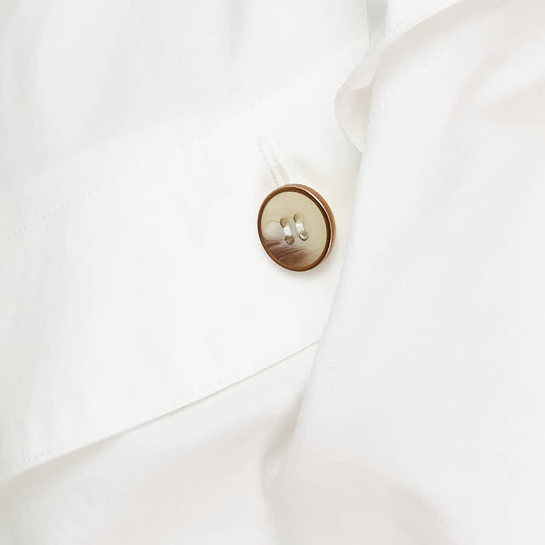 Zimmermann Valiant Utility Shirt in white with sculptural cape sleeves, asymmetric draped collar, and tortoiseshell button cuff detailing