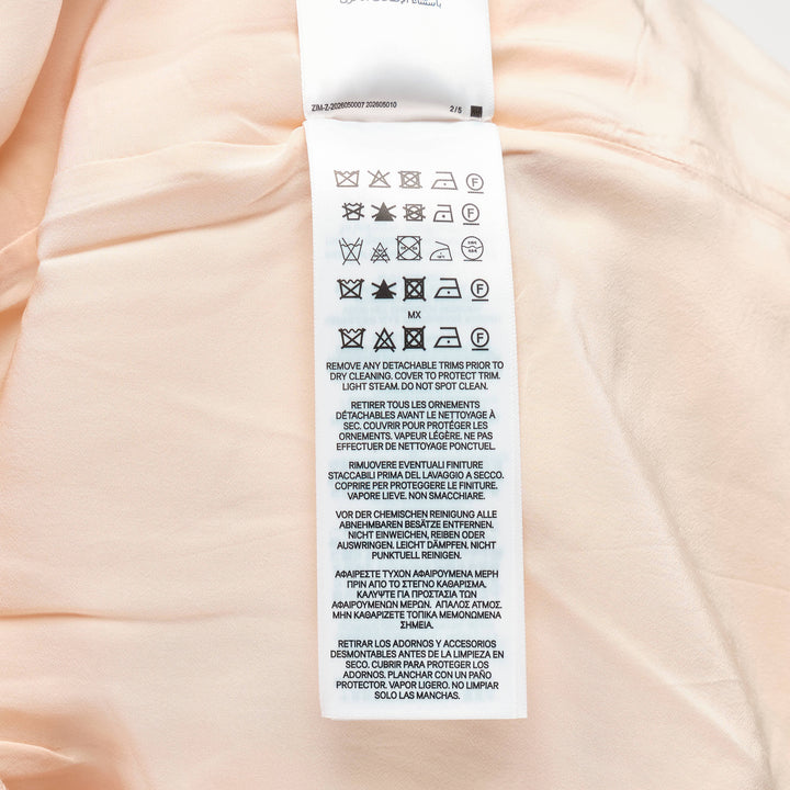 Zimmermann Valiant Tuck Shorts in blush pink with an all-over botanical floral print, featuring a full pleated silhouette, high waistband, and a striped sash bow tie at the front