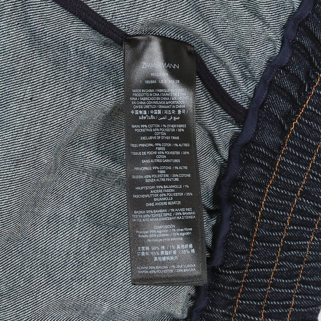 Zimmermann Denim Handkerchief Bomber Jacket in dark indigo with orange contrast topstitching, gathered ruched panels, gold-tone zip pockets, stand collar, and elasticated ribbed hem and cuffs
