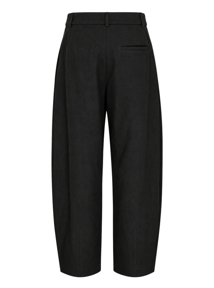 Lauren Manoogian black pleated taper trousers with a high waist and curved leg, shown from the front - view 2