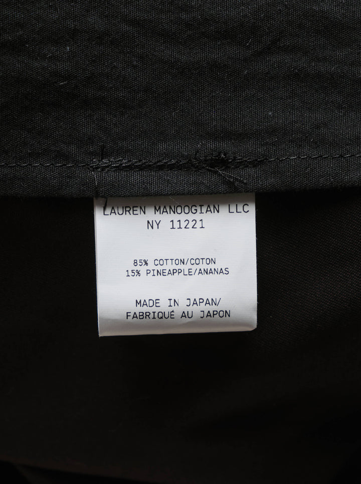 Lauren Manoogian black pleated taper trousers with a high waist and curved leg, shown from the front - view 4