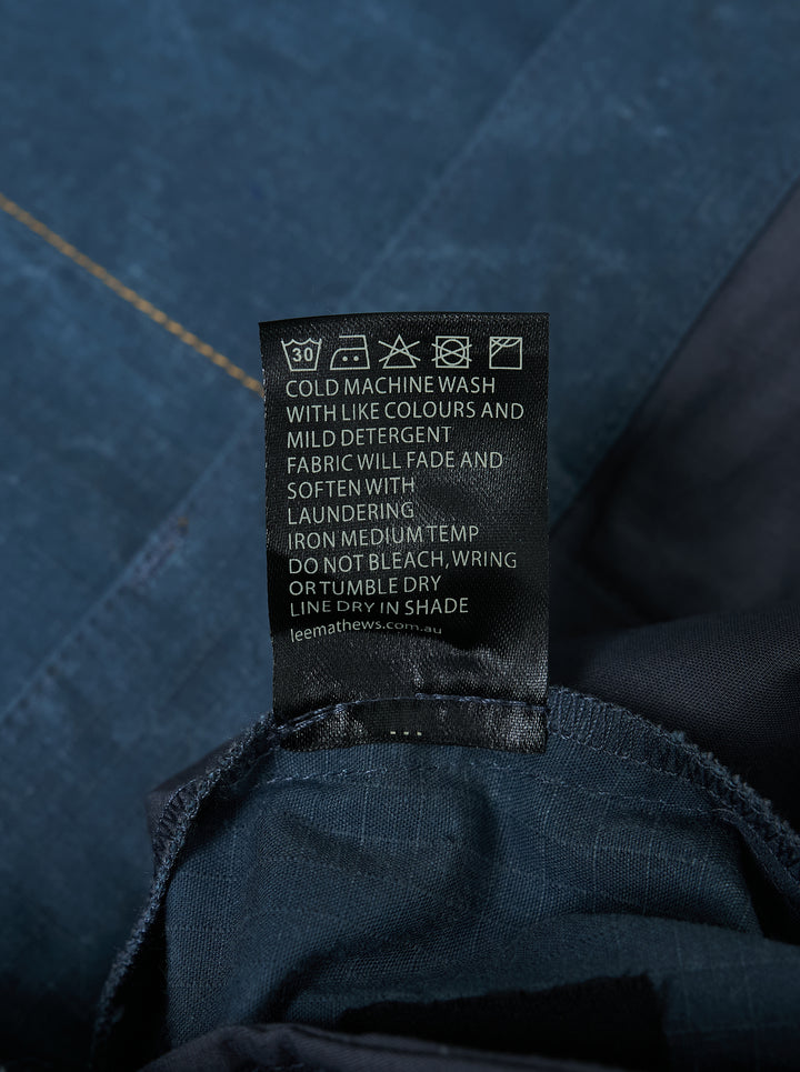 Lee Mathews Cecil Cotton Pants in crinkle-textured faded indigo blue, featuring a wide-leg silhouette, oversized patch pockets, and contrast topstitching throughout - view 3