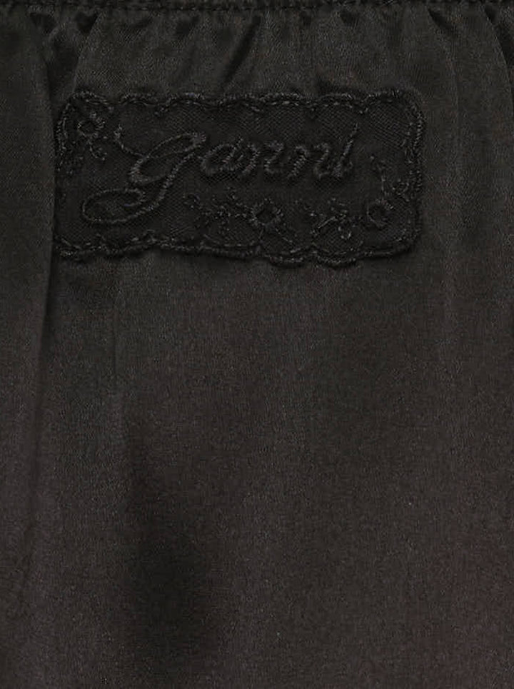 Ganni black fluid satin knee-length slip skirt with elasticated waist and tiered logo-embroidered lace frill hem - view 3