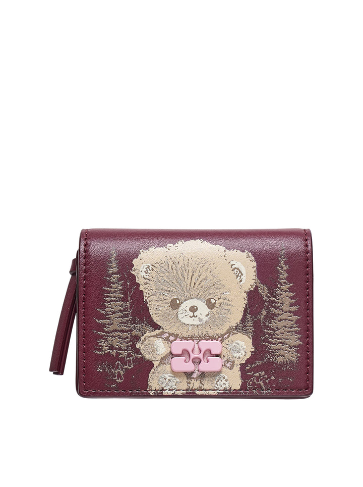 Ganni Bou Bear Print Card Holder in burgundy leather featuring an illustrated teddy bear and pine forest motif with a pink butterfly-knot clasp hardware detail