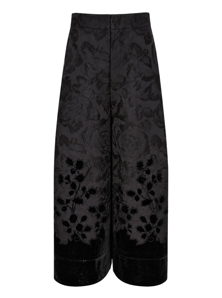 Biyan black lamé jacquard wide leg trousers with all-over rose brocade pattern, broderie anglaise cutwork floral hem border with beaded scallop edging, and velvet cuff finish, photographed flat on a white background