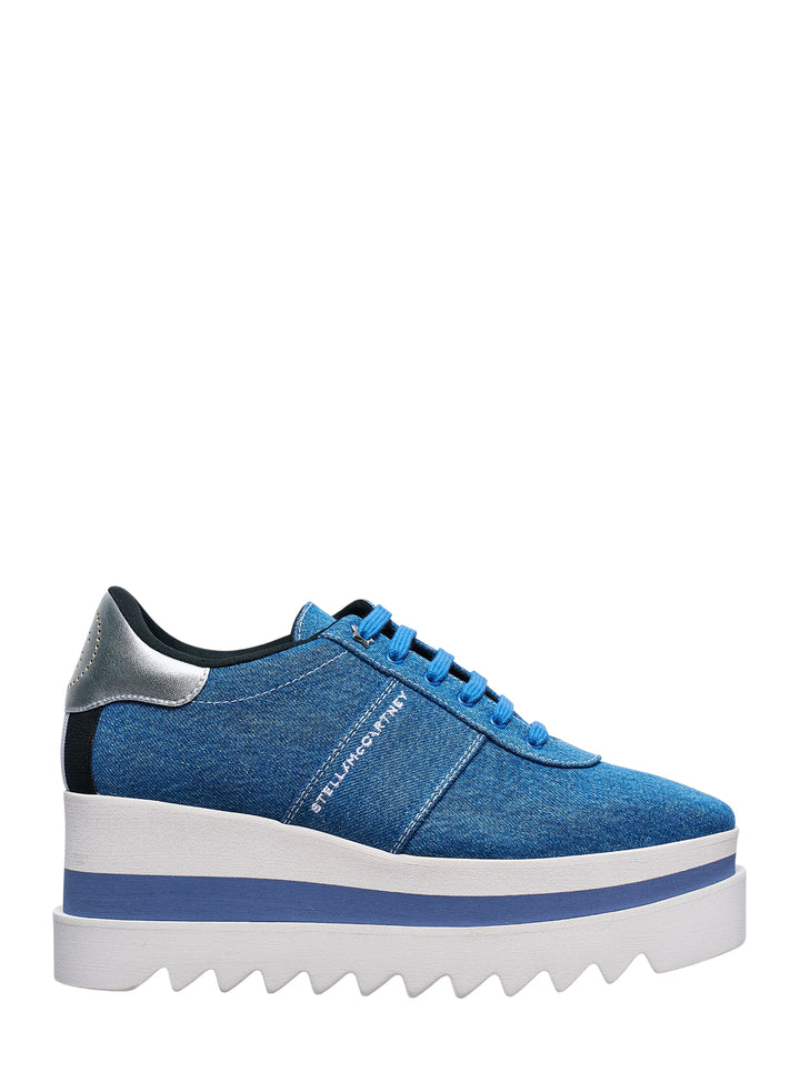 Stella McCartney Sneakelyse flatform sneaker in vintage washed blue denim with embroidered logo, silver heel counter, and a stacked white and blue striped platform sole with serrated tread