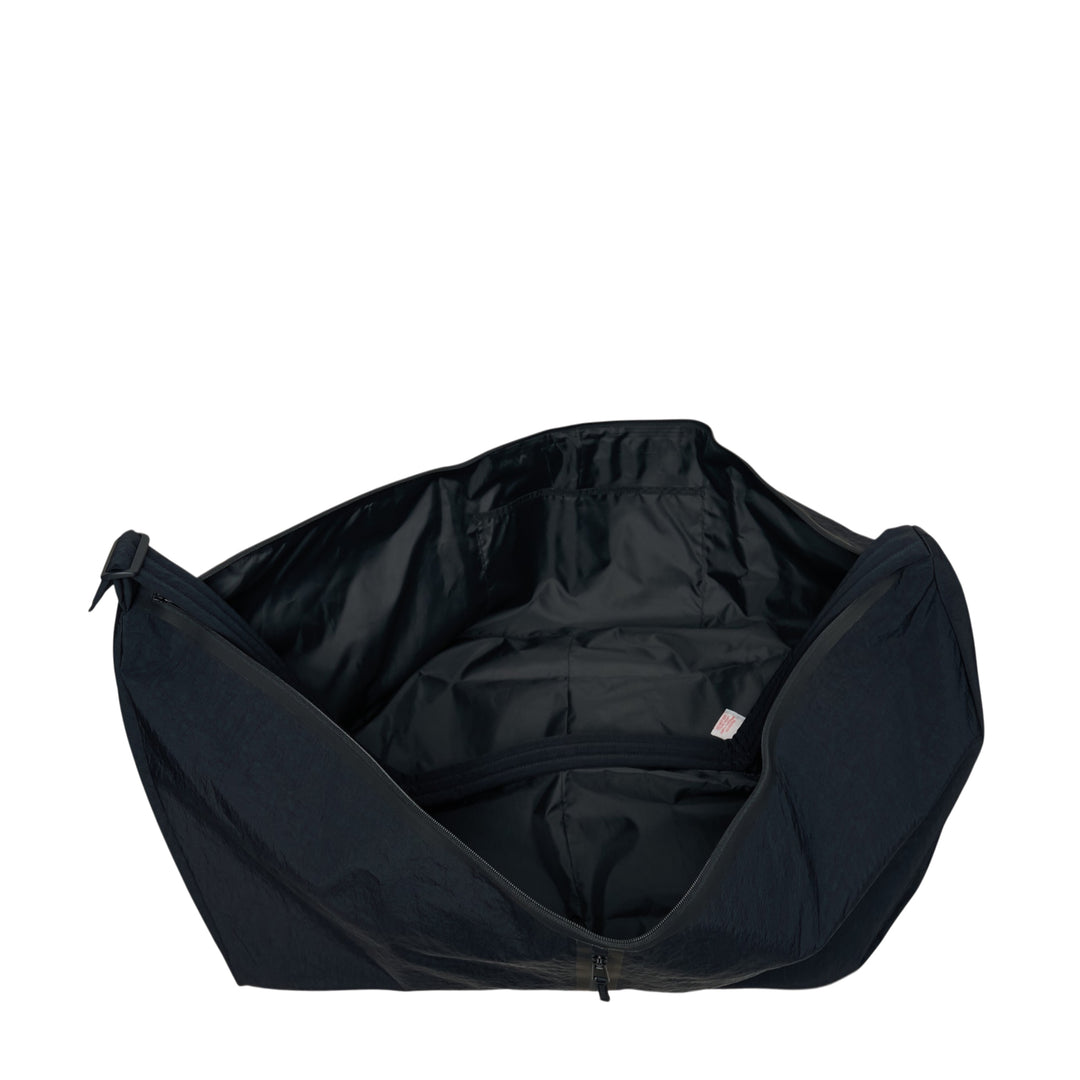 Fear of God ESSENTIALS x Eastpak Shell Bag Large in black, front view showing oversized body, wide shoulder strap, central zip closure, and co-branded woven label - view 3