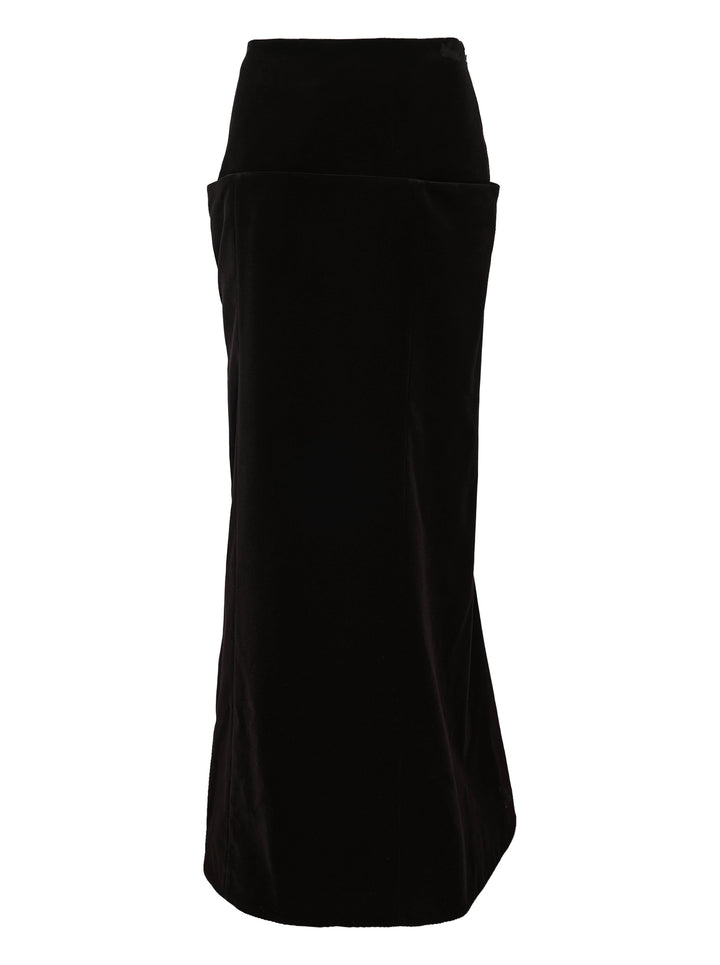 Alaïa black cotton velvet column maxi skirt with structured wide waistband, hip patch pockets, and a subtle flare at the hem, shown on a white background