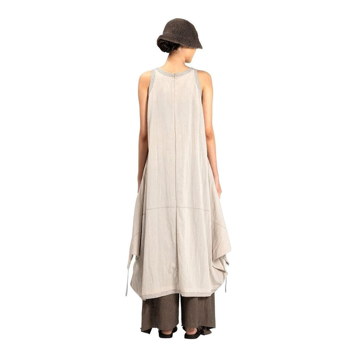 Model wearing an Anaabu black sleeveless midi dress with a voluminous A-line silhouette, asymmetric handkerchief hemline, and fine metallic stud trim at the neckline and hem - packshot