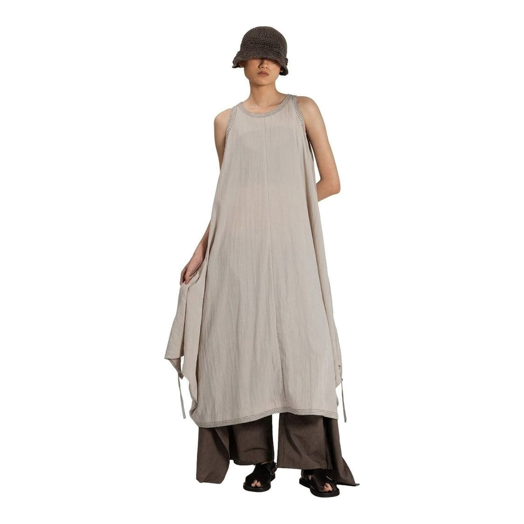 Model wearing an Anaabu black sleeveless midi dress with a voluminous A-line silhouette, asymmetric handkerchief hemline, and fine metallic stud trim at the neckline and hem - packshot