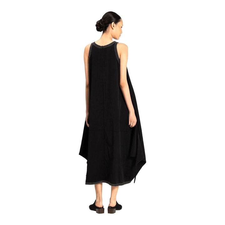 Model wearing an Anaabu black sleeveless midi dress with a voluminous A-line silhouette, asymmetric handkerchief hemline, and fine metallic stud trim at the neckline and hem - packshot