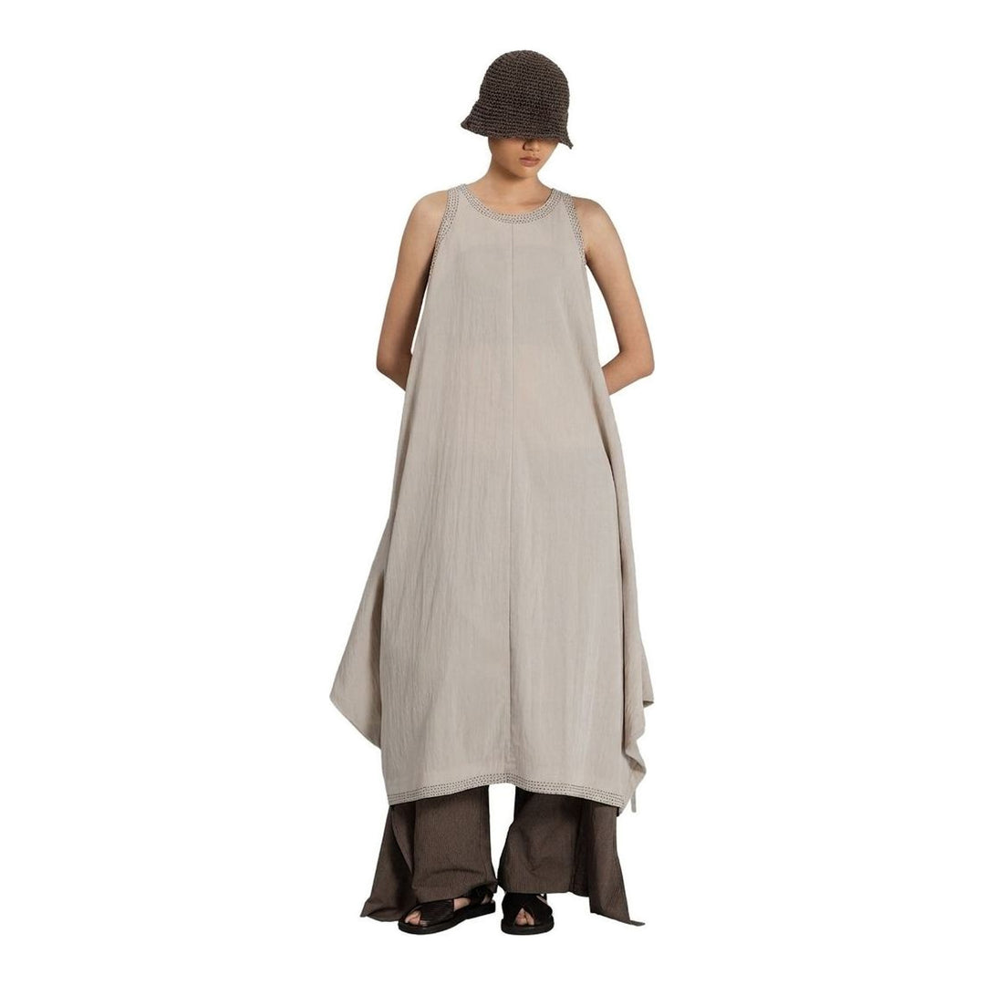 Model wearing an Anaabu black sleeveless midi dress with a voluminous A-line silhouette, asymmetric handkerchief hemline, and fine metallic stud trim at the neckline and hem - packshot