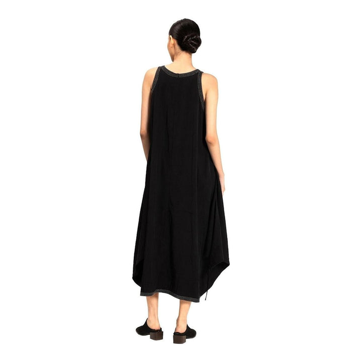 Model wearing an Anaabu black sleeveless midi dress with a voluminous A-line silhouette, asymmetric handkerchief hemline, and fine metallic stud trim at the neckline and hem - packshot