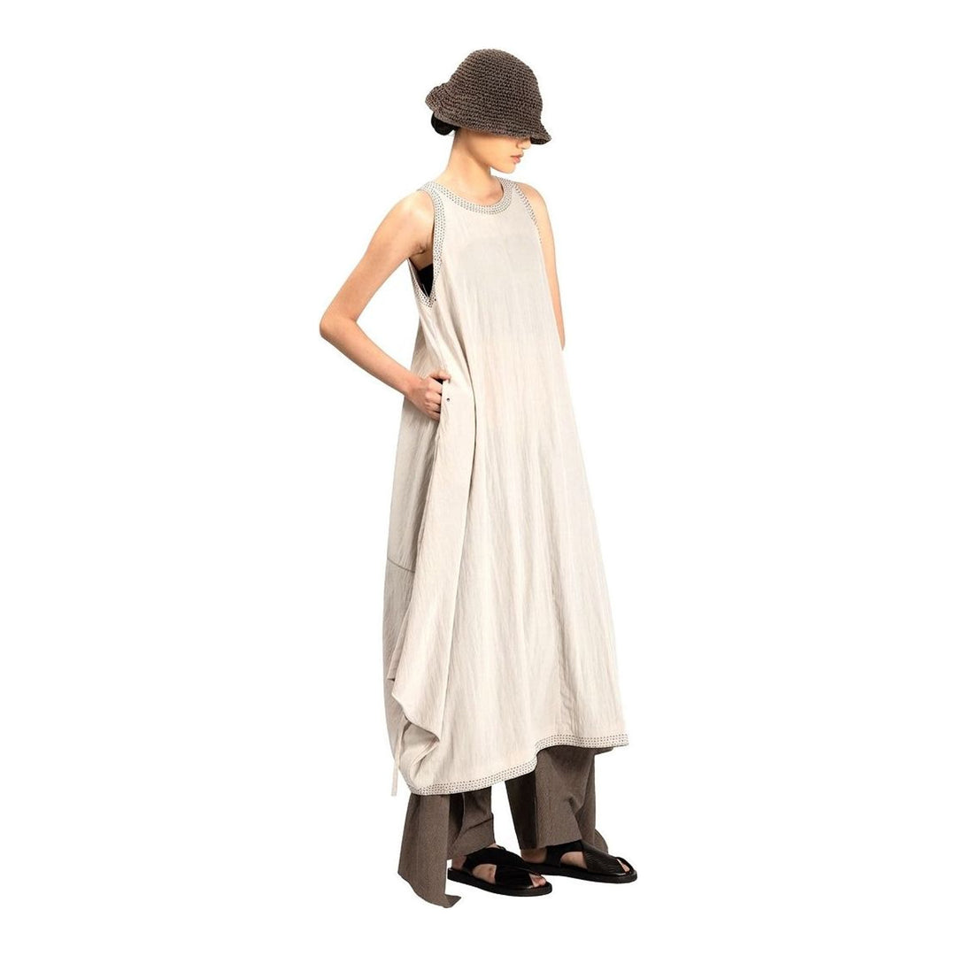 Model wearing an Anaabu black sleeveless midi dress with a voluminous A-line silhouette, asymmetric handkerchief hemline, and fine metallic stud trim at the neckline and hem - packshot