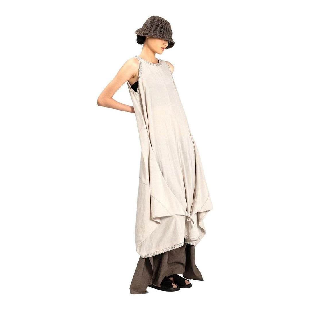 Model wearing an Anaabu black sleeveless midi dress with a voluminous A-line silhouette, asymmetric handkerchief hemline, and fine metallic stud trim at the neckline and hem - packshot