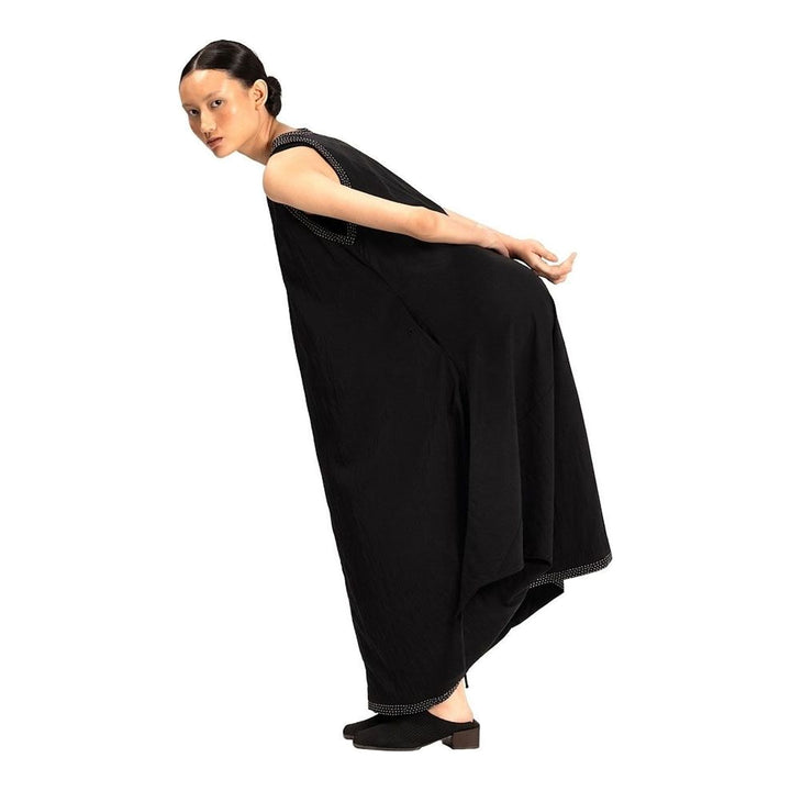 Model wearing an Anaabu black sleeveless midi dress with a voluminous A-line silhouette, asymmetric handkerchief hemline, and fine metallic stud trim at the neckline and hem - packshot