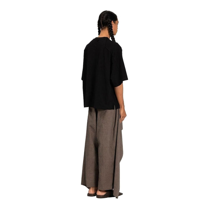 Model wearing the Anaabu Boxy Short Sleeve Tee in black — an oversized, dropped-shoulder silhouette styled over a taupe wide-leg trouser skirt - packshot
