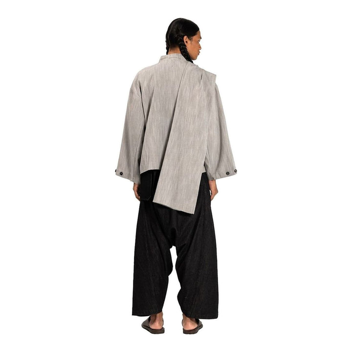 Model wearing the Anaabu Shawl Jacket in black — a draped wrap-style jacket with oversized shawl collar and self-tie belt, styled over a black turtleneck and olive wide-leg trousers - packshot