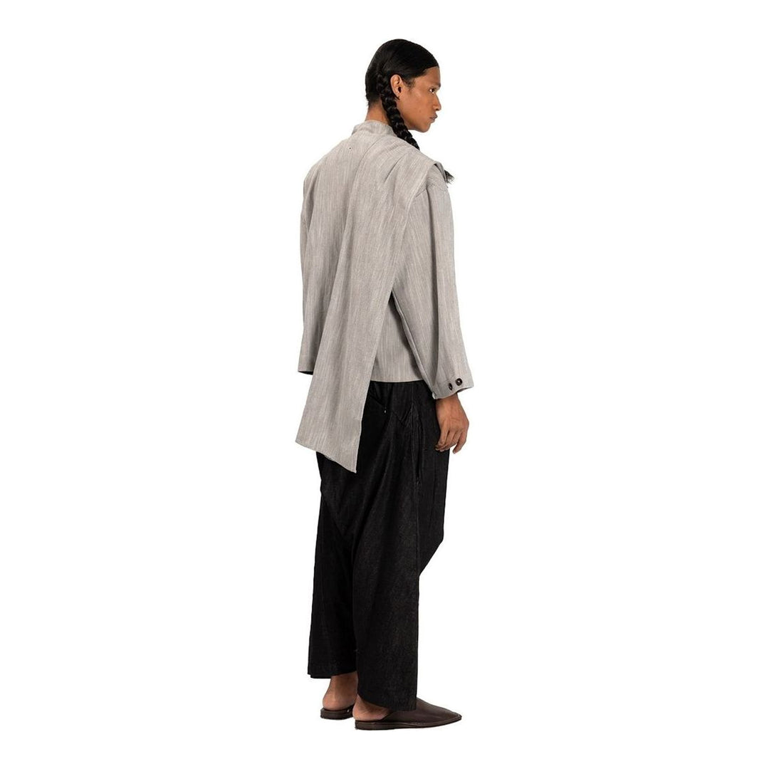 Model wearing the Anaabu Shawl Jacket in black — a draped wrap-style jacket with oversized shawl collar and self-tie belt, styled over a black turtleneck and olive wide-leg trousers - packshot