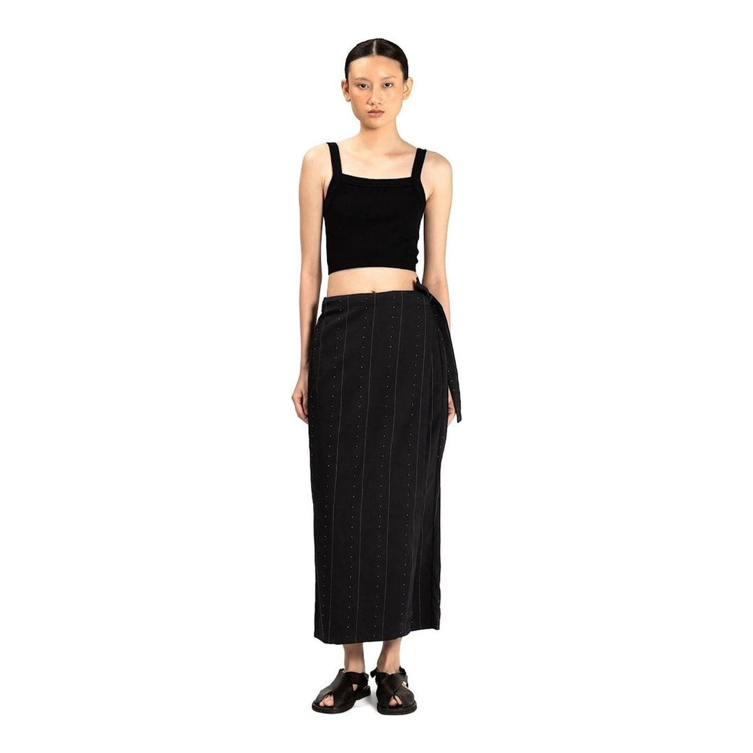 Model wearing Anaabu The Skants — black wide-leg cropped pants with large draped overlay panels featuring pinstripe and dot print, paired with a black square-neck crop top and leather sandals - packshot