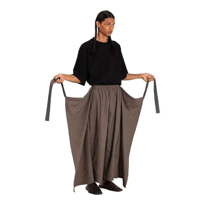 Model wearing Anaabu The Skants — black wide-leg cropped pants with large draped overlay panels featuring pinstripe and dot print, paired with a black square-neck crop top and leather sandals - packshot