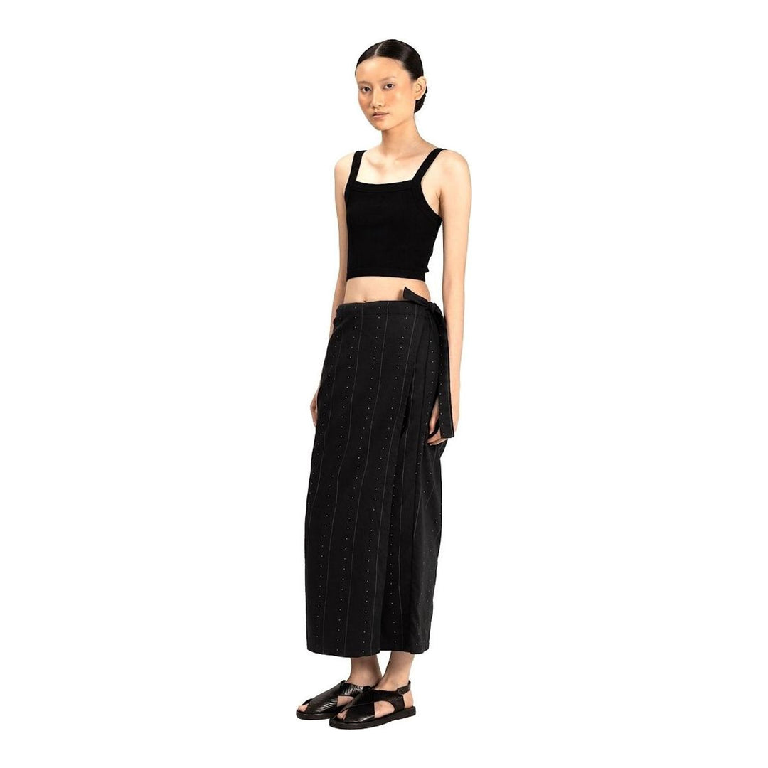 Model wearing Anaabu The Skants — black wide-leg cropped pants with large draped overlay panels featuring pinstripe and dot print, paired with a black square-neck crop top and leather sandals - packshot