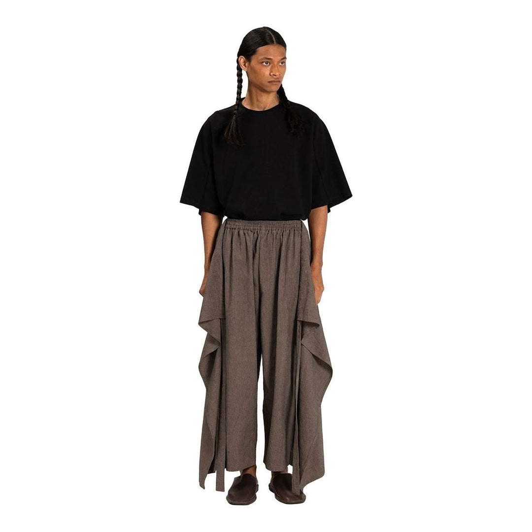 Model wearing Anaabu The Skants — black wide-leg cropped pants with large draped overlay panels featuring pinstripe and dot print, paired with a black square-neck crop top and leather sandals - packshot