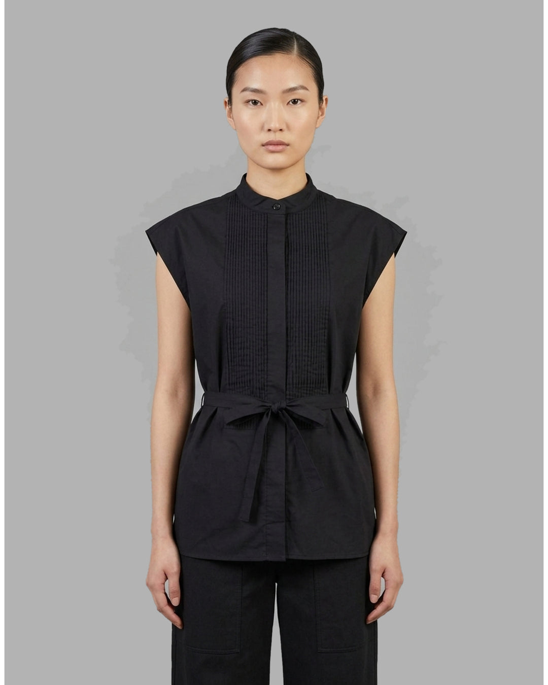 Black sleeveless cotton shirt with pintucked bib front, mandarin collar and self-fabric waist tie - front