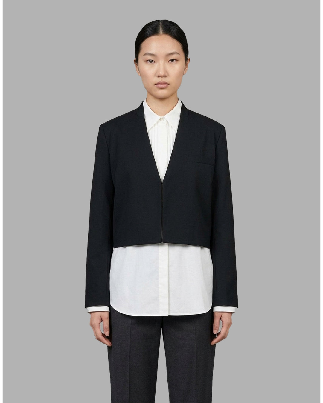Black collarless cropped jacket with asymmetric wrap front and chest flap detail by Club21 Collection - front
