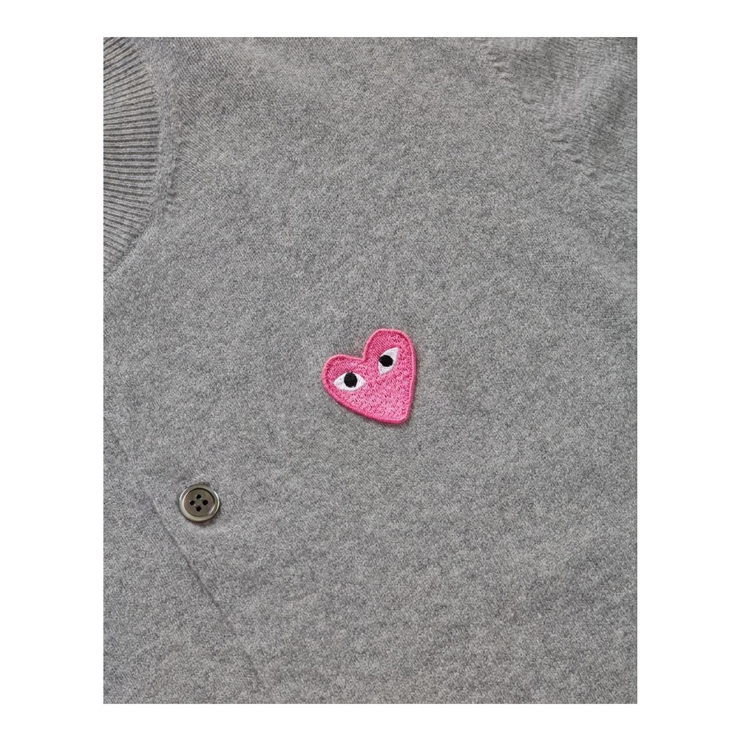 Comme des Garçons PLAY black round neck cardigan with embroidered pink heart emblem patch and button-through front fastening, flat lay view - packshot