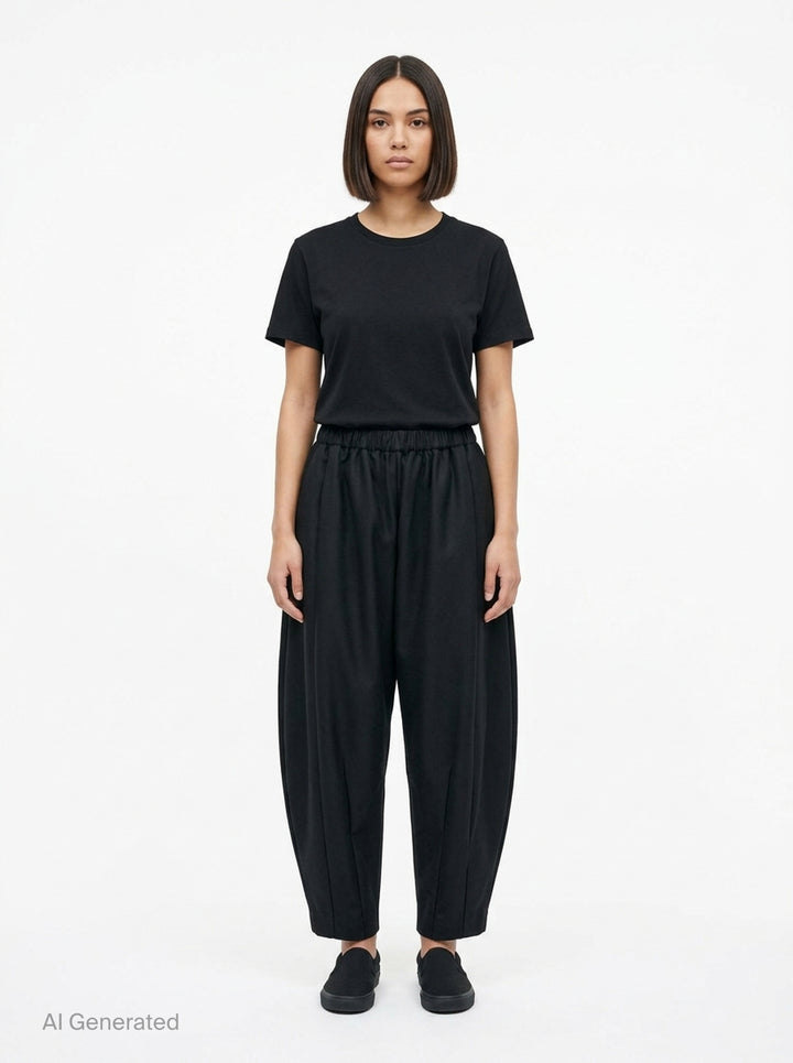 Comme des Garçons black rounded silhouette balloon-leg pants with elasticated waistband and structured vertical seaming, laid flat on white background - front
