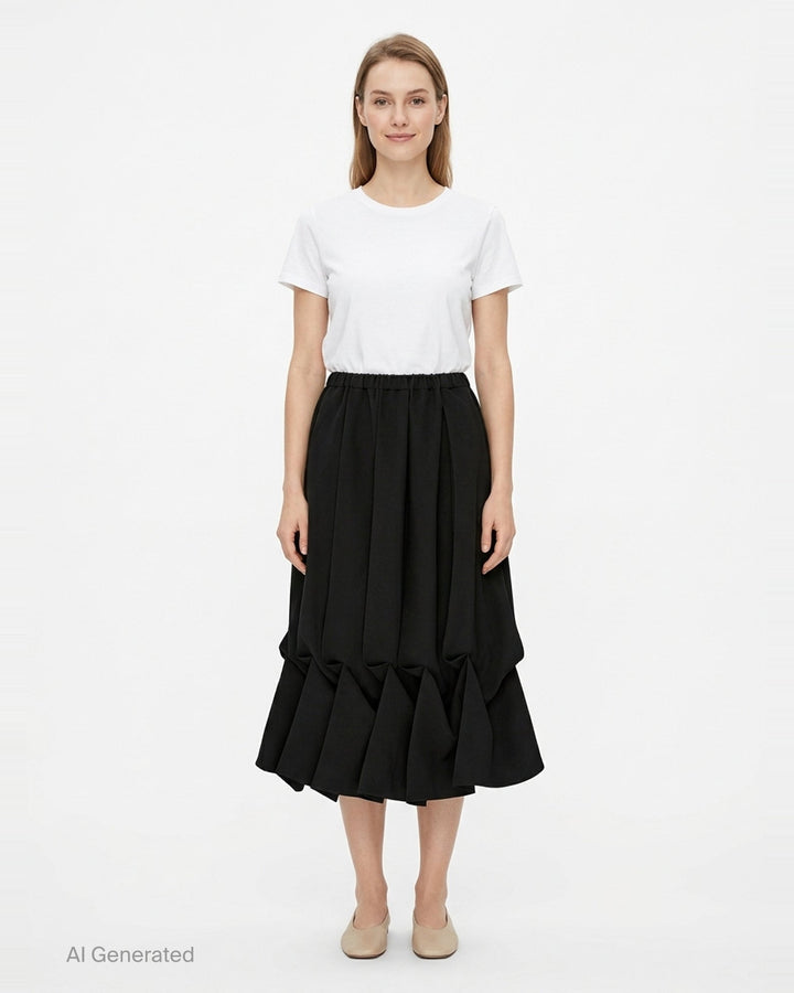 Enfold Draped Hem Midi Skirt in black, featuring vertical pleating, elasticated waistband, and a sculptural gathered ruffle hem, shown on a white background - front