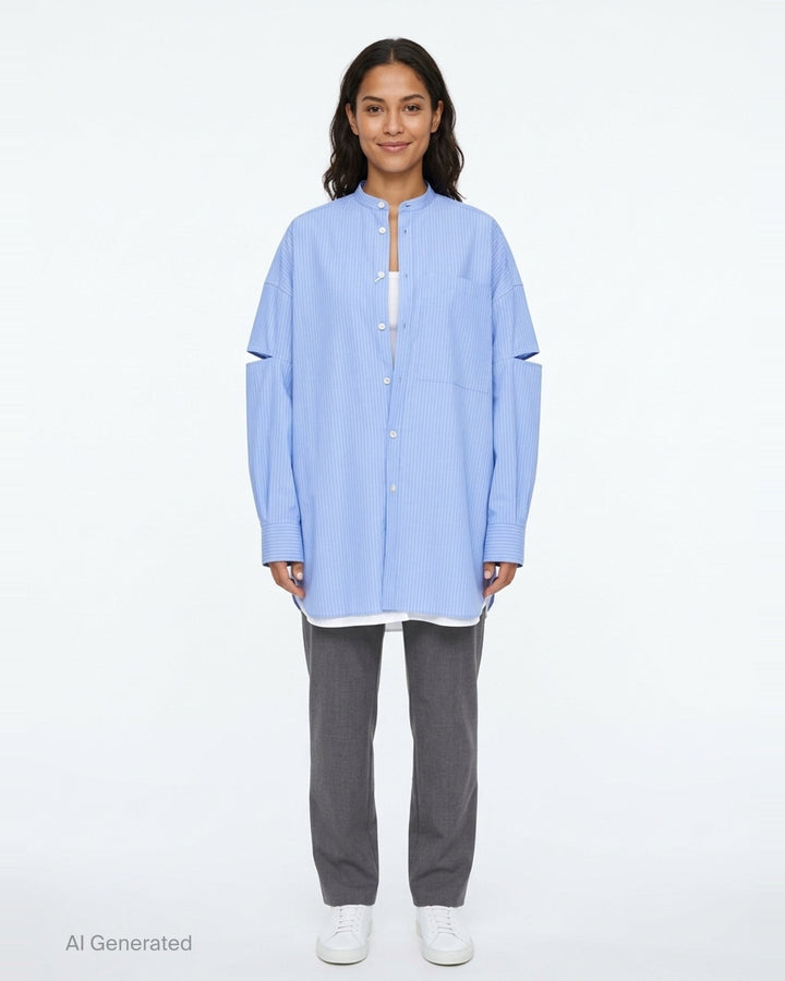 Enfold pale blue pinstripe oversized shirt with deconstructed cut-out sleeves, mandarin collar, white button placket, and a contrast white underlayer at the hem - front