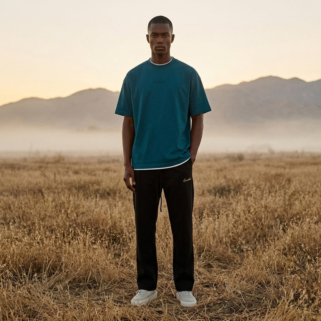 Fear of God ESSENTIALS Classic Double Layer Tee in black with white undertee at the neckline and hem and tonal embroidered logo at the chest - lifestyle