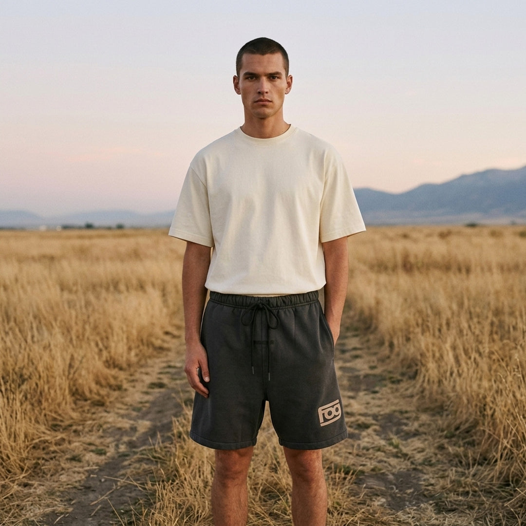 Fear of God Essentials washed black fleece shorts with drawstring waist and beige 'fog' logo print at the hem - lifestyle