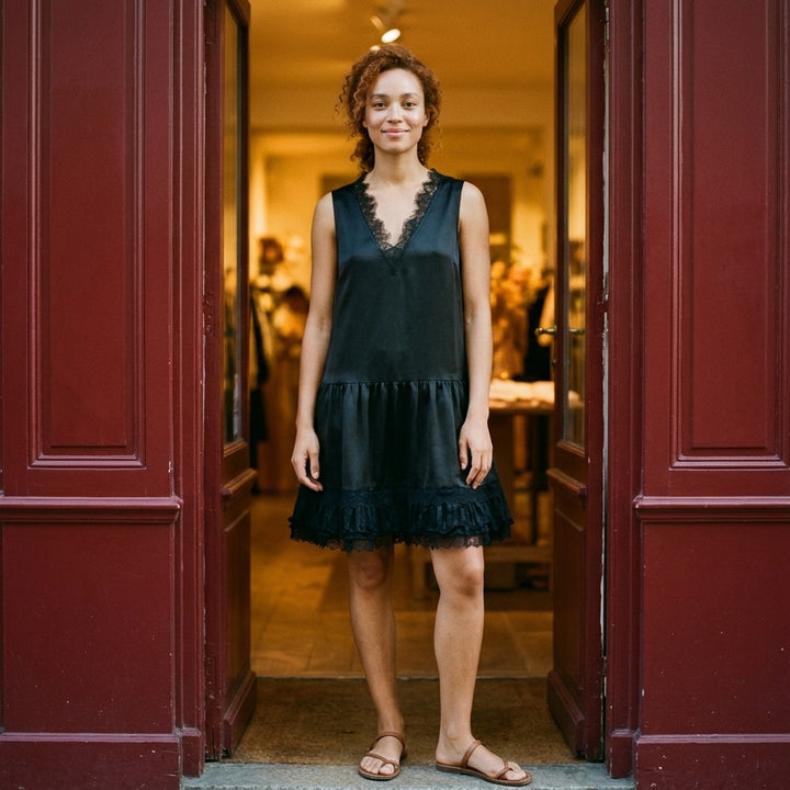 GANNI black fluid satin sleeveless mini dress with lace-trimmed V-neckline, tie back detail and tiered pleated lace ruffle hem - lifestyle