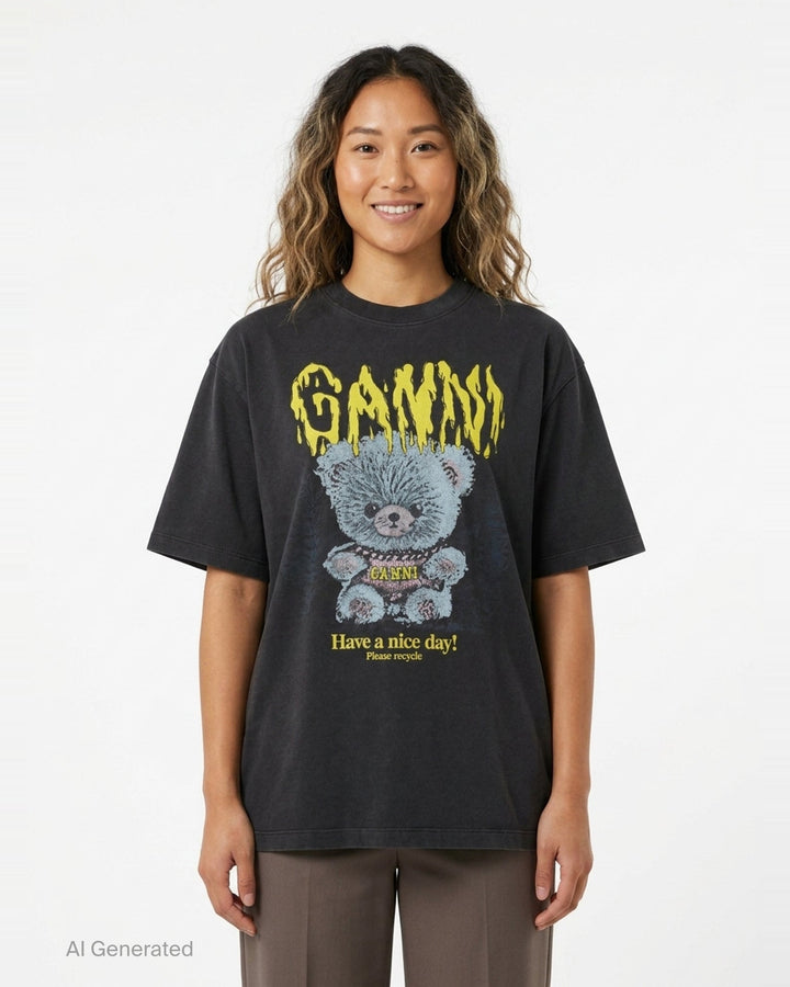 Ganni Heavy Cotton Forest Ted T-shirt in washed black, featuring a yellow drip-style Ganni logo above a teddy bear mascot graphic and 'Have a nice day! Please recycle' slogan print - front