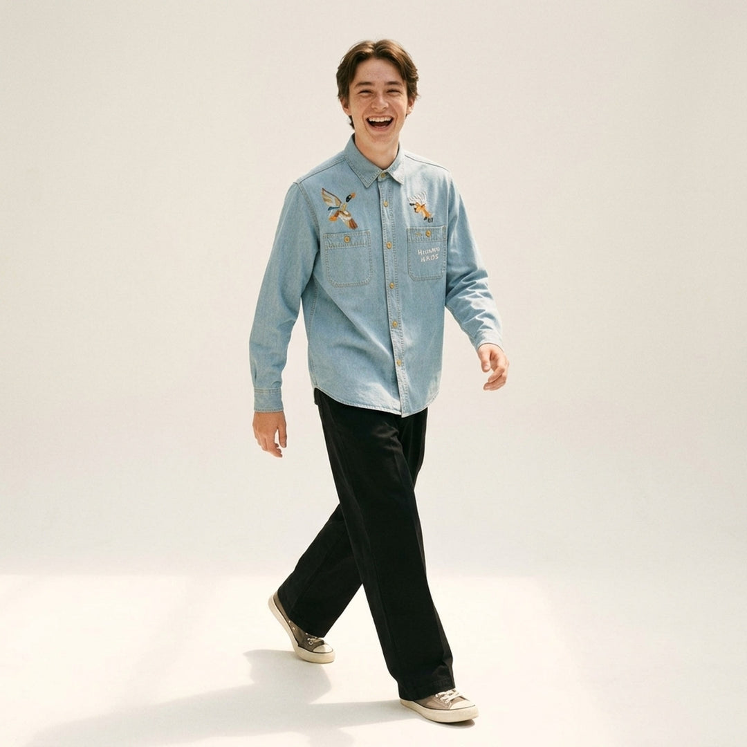 Human Made Embroidered Long Sleeve Chambray Shirt in light-wash denim, featuring a flying duck and deer head embroidery above dual chest pockets, with amber buttons and Human Made script embroidery - lifestyle