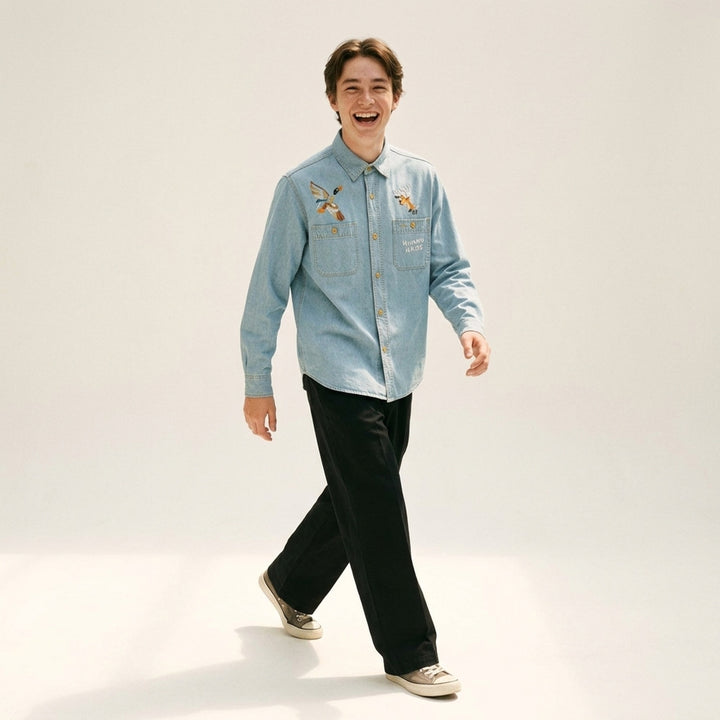 Human Made Embroidered Long Sleeve Chambray Shirt in light-wash denim, featuring a flying duck and deer head embroidery above dual chest pockets, with amber buttons and Human Made script embroidery - lifestyle