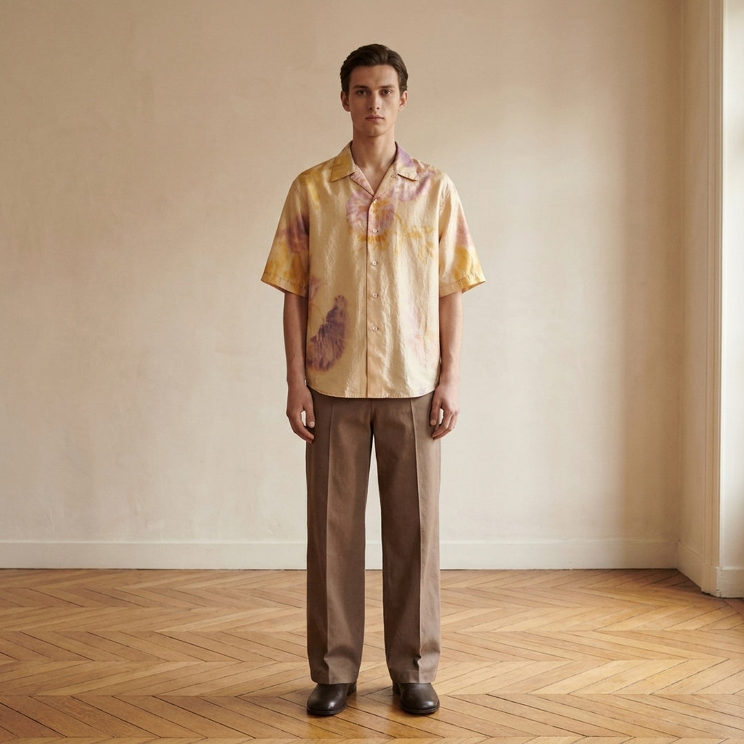 Lemaire short sleeve summer shirt in silk with a blurred watercolour floral print in yellow, pink and violet, shown with an open camp collar and button front - lifestyle