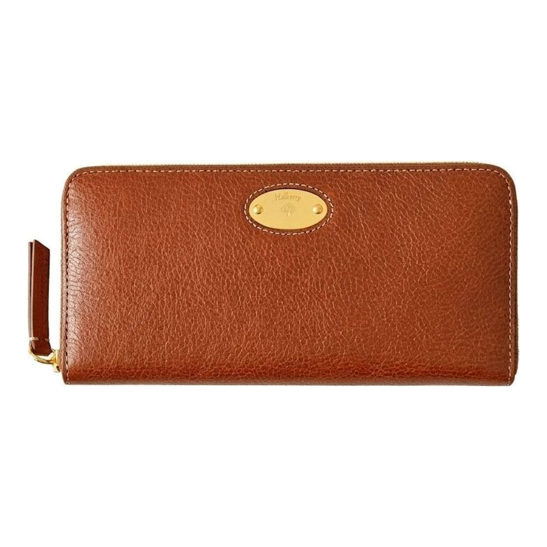 Mulberry Plaque 8 CC Zip Purse in tan grained leather with gold-tone oval plaque hardware and contrast topstitching, laid flat on a neutral background - packshot