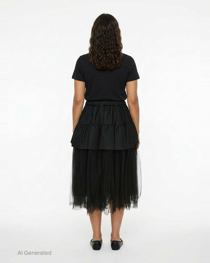 Noir Kei Ninomiya black tiered ruffle skirt with gathered elastic waist and sheer tulle underlayer, midi length, on white background - back