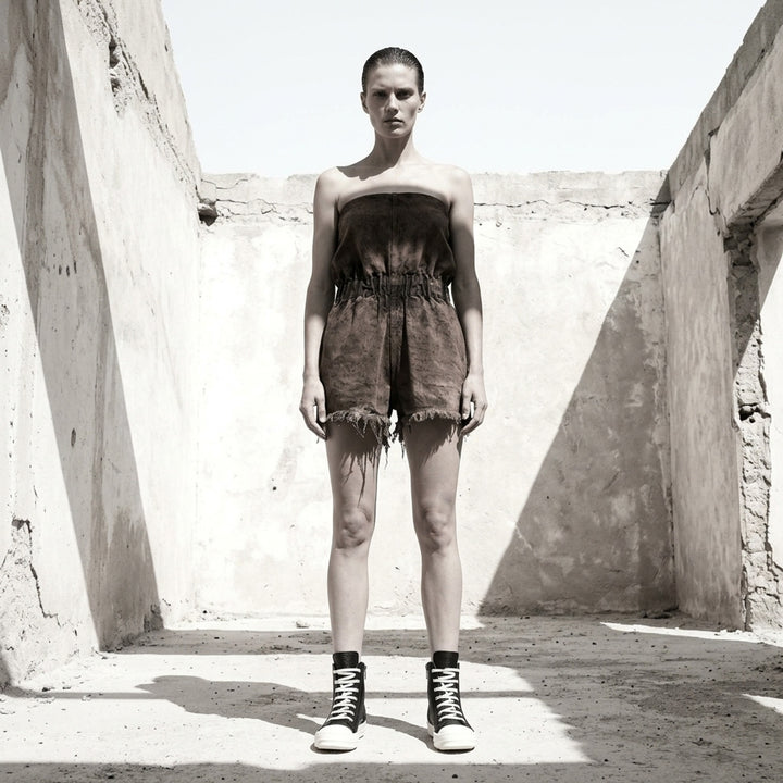 Rick Owens Crater Shorts in 13oz dust-wash brown denim — rear view showing strapless bandeau romper silhouette, gathered elasticated waist, and raw frayed hem - lifestyle