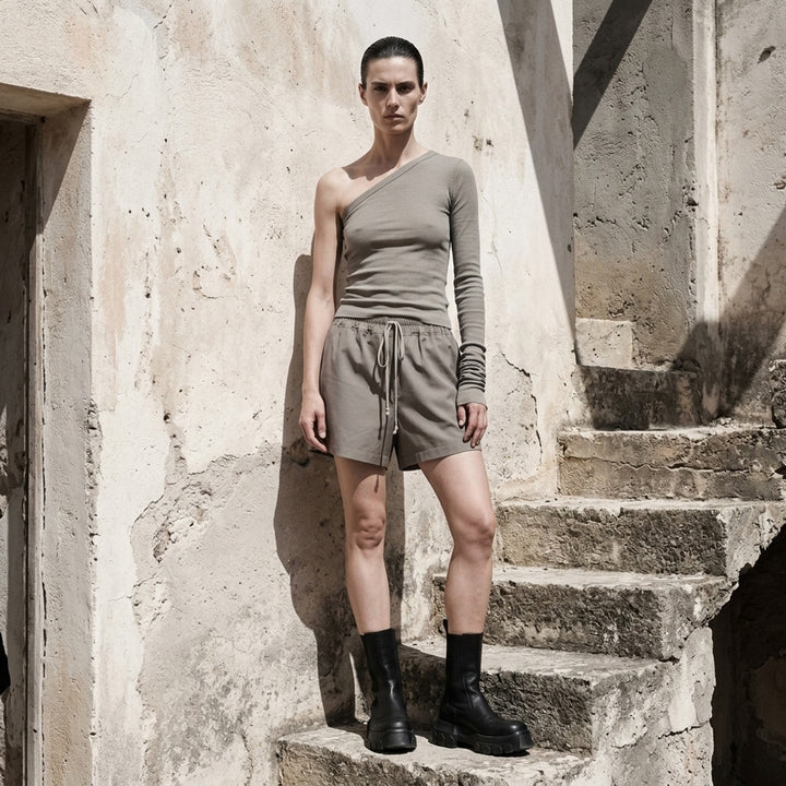Rick Owens Ziggy black one-shoulder ribbed knit top with a single long ruched sleeve and cropped hem, photographed on a white background - lifestyle
