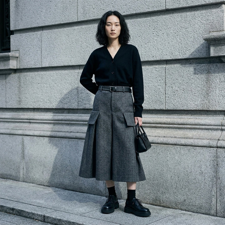 sacai Double-Faced Herringbone Midi Skirt in charcoal grey, featuring voluminous pleats, dual cargo patch pockets, and a black leather adjustable belt at the waist - lifestyle