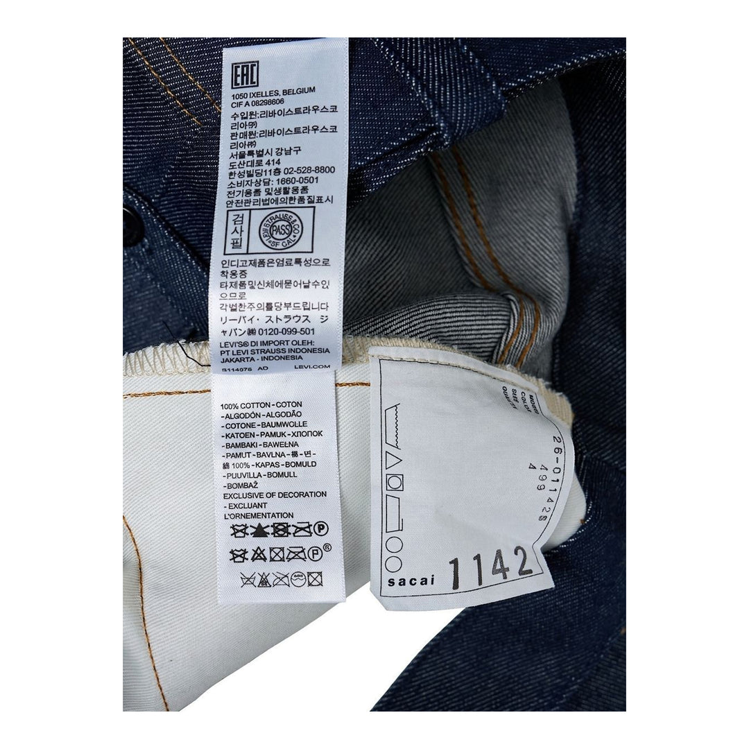 sacai wide-leg washed blue jeans with layered waistband and black belt with metal buckle, shown from the front - packshot