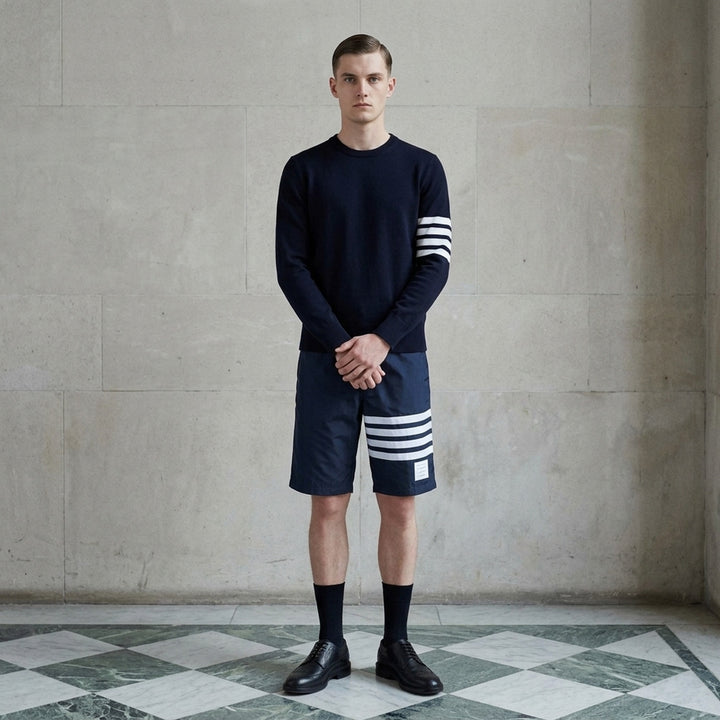 Thom Browne grey board shorts with 4-bar white stripe detail on one leg, red and white braided drawstring waist, and woven logo label at the hem - lifestyle